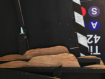 Two naked soldiers laying and looking at a board that is put there to deliberately separate them, so that they don't divert their attention toward each other.